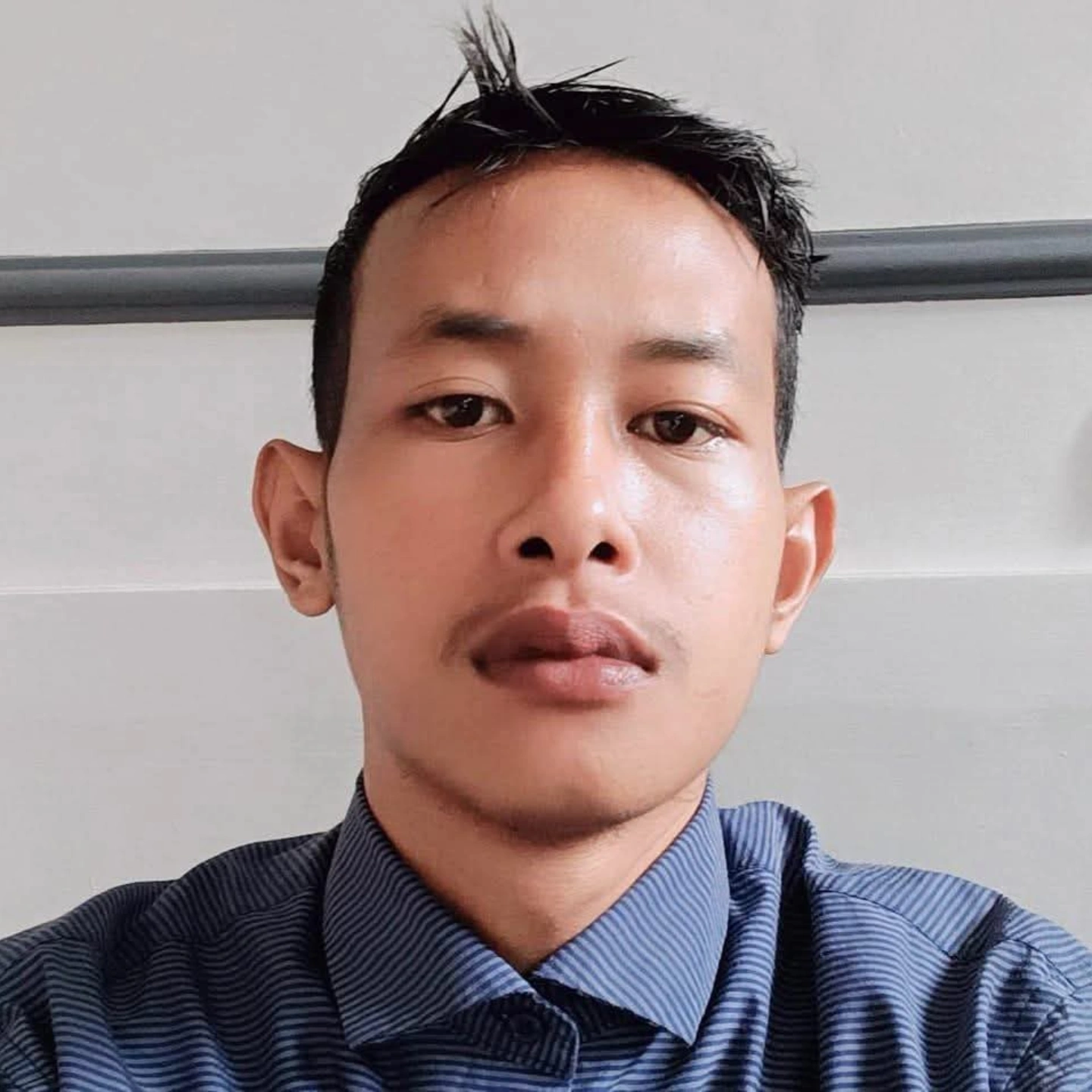 Professional portrait of Adiatma Wasara, a frontend developer wearing smart casual attire with a genuine smile, standing in a modern office environment